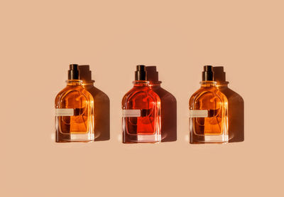 Three different perfume bottles on a pastel beige background in the sunlight. flat lay, top view