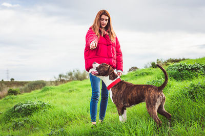 Full length of young woman with horse on field