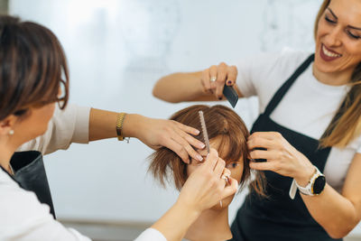 Hairdressers training with mannequin head in education center. professional female hairdresser 