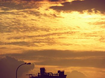 Silhouette of city against dramatic sky during sunset