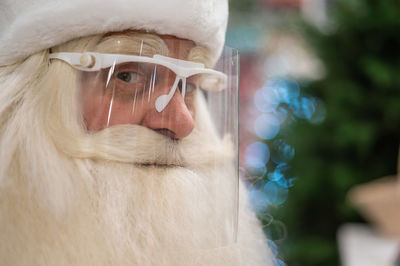 Close-up portrait of santa clause wearing face shield