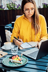 Time management for freelancers. woman freelancer writes in a notebook and working with laptop