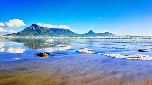 Scenic view of sea and mountains against blue sky