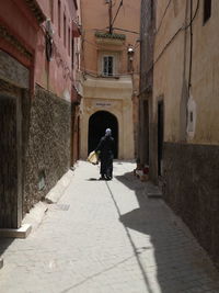 Woman walking on footpath amidst buildings in city