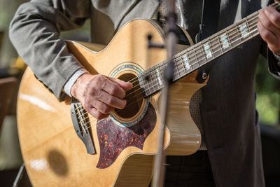 Midsection of well-dressed man playing guitar