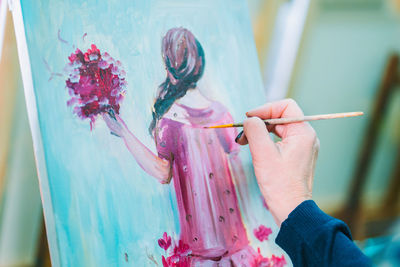 Close-up of woman hand painting on canvas in studio