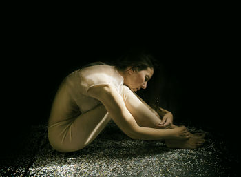 Side view of woman sitting on field