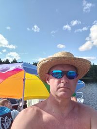 Portrait of shirtless man against sky