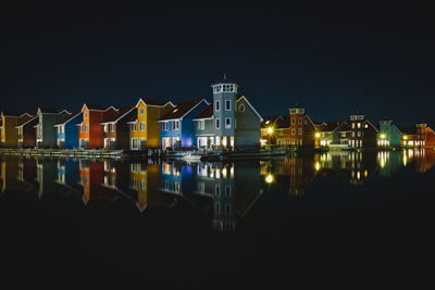 Illuminated pier by river against sky at night