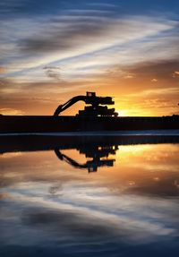Silhouette boat in lake against sky during sunset