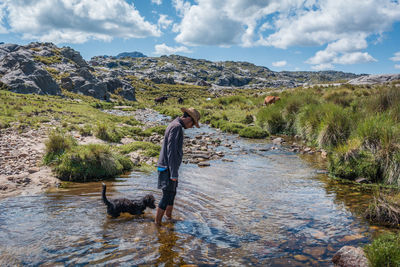 Woman with dog in water against sky