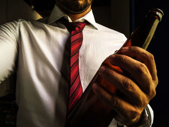 Man with tie shirt holding a bottle of beer