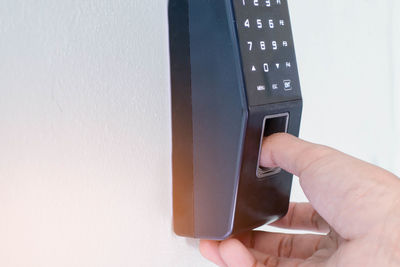 Midsection of person holding camera against wall