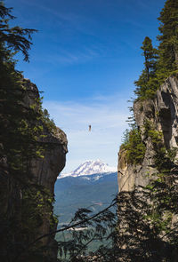 Extreme sport highliner with scenic view of mountains against blue sky