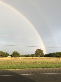 Scenic view of rainbow over field against sky