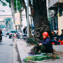 Mid adult woman selling flowers on footpath