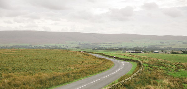 Road amidst field against sky