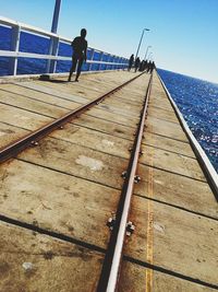 Tilt image of people walking on pier over sea against clear sky