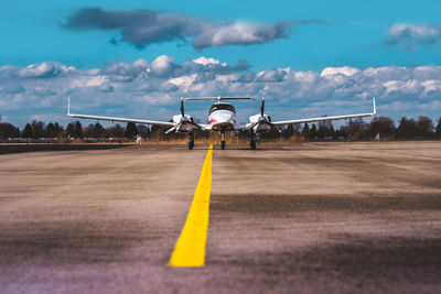 Airplane on airport runway against sky