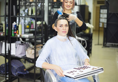 Cheerful hairdresser dying hair of customer at salon