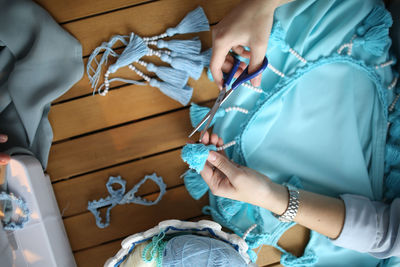 Craftswoman knits and assembles braid, close-up. real light interior, wooden table, top view. 