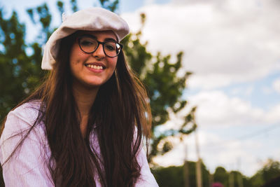 Portrait of smiling teenager girl sitting against tree