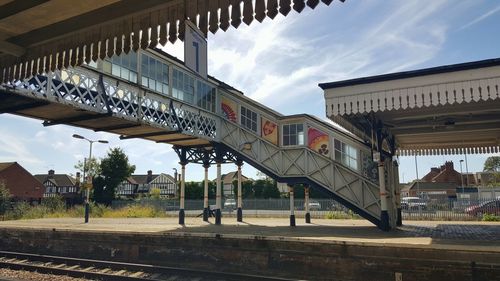 People at railroad station against sky