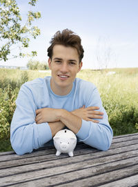 Portrait of young man with piggy bank on table