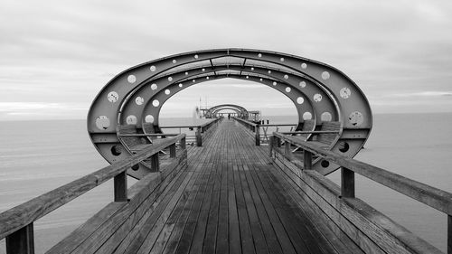 Wooden pier over sea against cloudy sky