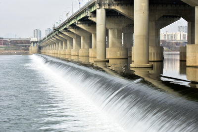 Bridge over river in city against sky