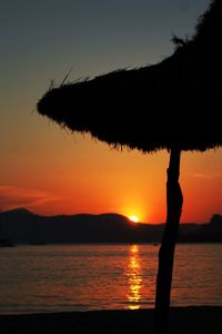 Silhouette tree by lake against sky during sunset