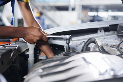 Midsection of mechanic repairing car