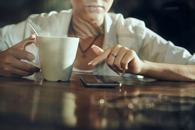 Midsection of man holding coffee cup on table