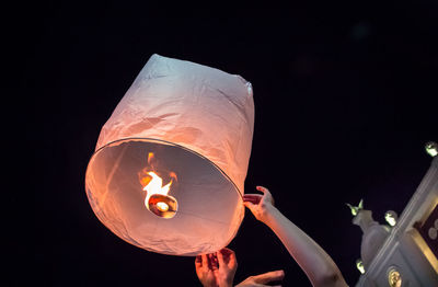 Low angle view of illuminated lantern against star shape at night