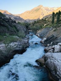 Stream flowing through rocks against sky