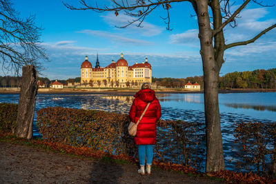 Rear view of woman standing by plants against sky