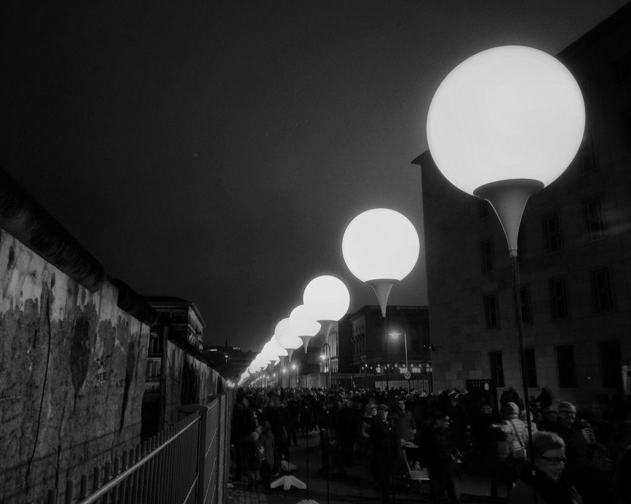 architecture, built structure, illuminated, lighting equipment, night, building exterior, low angle view, street light, arch, sky, clear sky, city, incidental people, electric light, large group of people, men, ceiling, outdoors, building