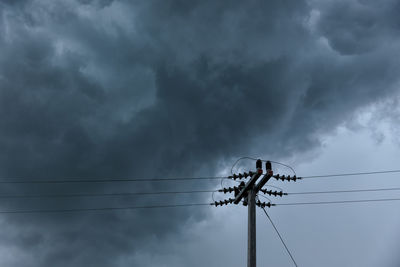 Low angle view of electricity pylon against cloudy sky