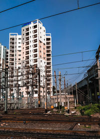 Railroad tracks by buildings against clear blue sky