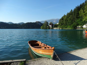 Boat moored on lake against sky