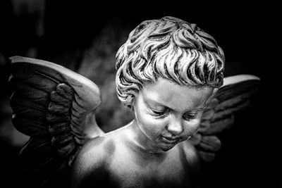 Close-up of boy statue against black background