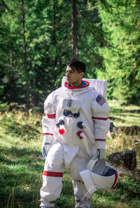 Man walking while wearing spacesuit in forest