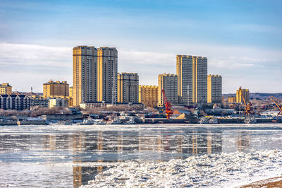 Modern buildings in city against sky during winter