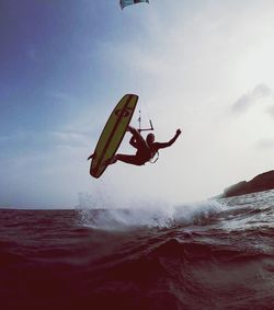 Low angle view of person surfing in sea against sky