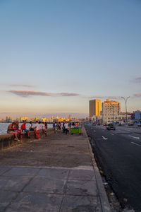 People on road against sky at sunset