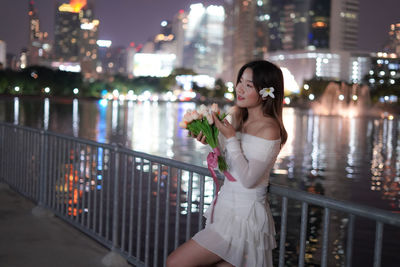 Portrait of young woman standing in city at night