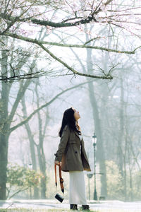 Rear view of woman standing in forest during winter