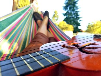 Low section of woman relaxing on hammock with guitar