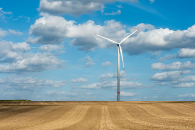 Wind turbines on field against sky