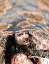 Portrait of smiling young woman amidst curtain